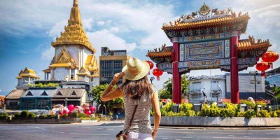 A tourist woman on sightseeing tour stands in front of the Chinatown Gate at the famous Yaowarat Road, Bangkok, Thailand